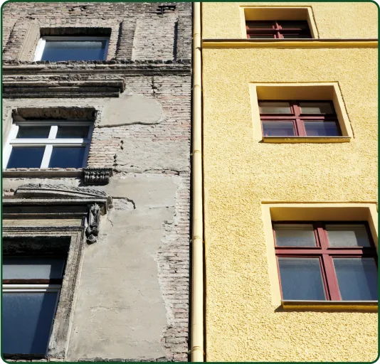 Nebeneinander stehende Hausfassaden, eine alt und zerfallen, die andere neu in gelbem Putz mit roten Fenstern.